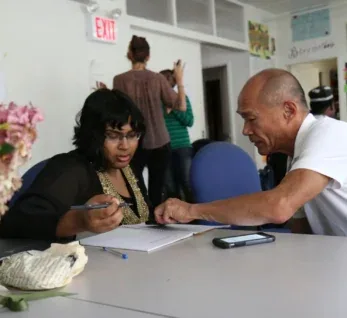 Two people working together at a community table